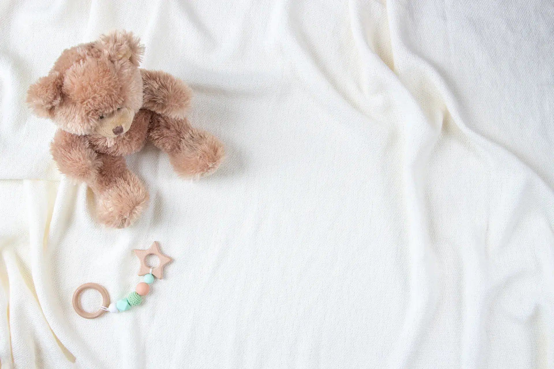 Ours en peluche avec hochet sur tissu blanc