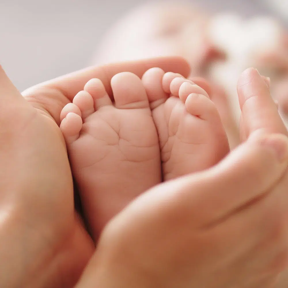 Pieds de bébé tenus dans des mains