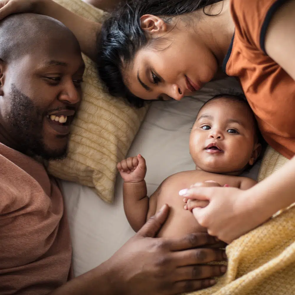 Famille souriante avec bébé allongé sur le lit